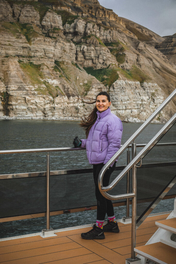 girl with goggles standing on a boat in the arctic ocean